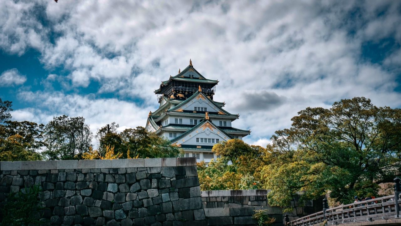 El castillo de Osaka asomando sobre su muralla de piedra, entre árboles