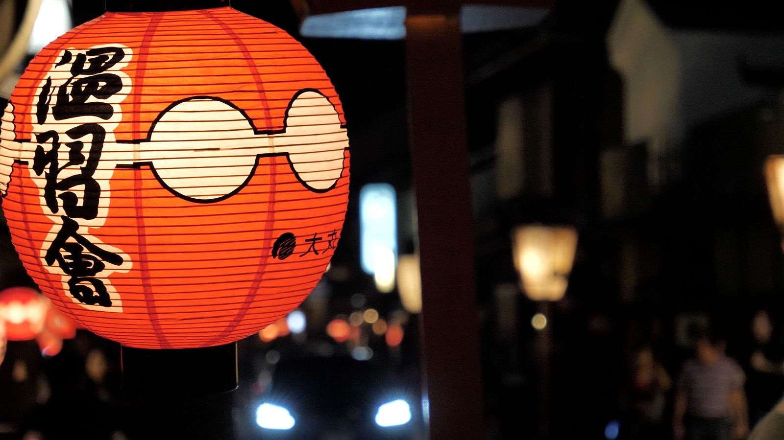 Un farolillo de papel rojo encendido en una calle japonesa de noche