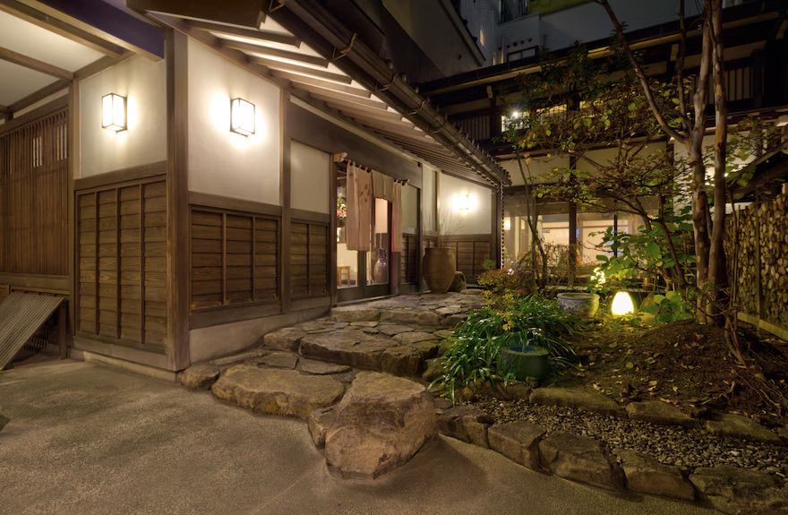 Pasillo de madera de un ryokan junto a un jardín, de noche