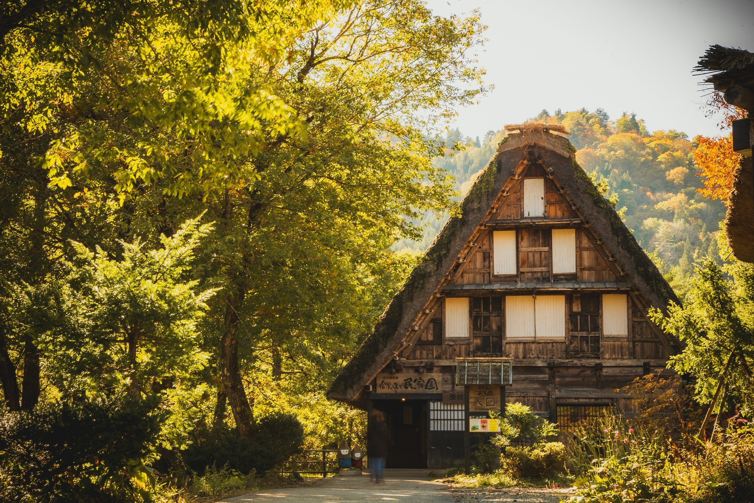 Casa de tejado de paja gasshō-zukuri en Shirakawa-go, con montañas detrás